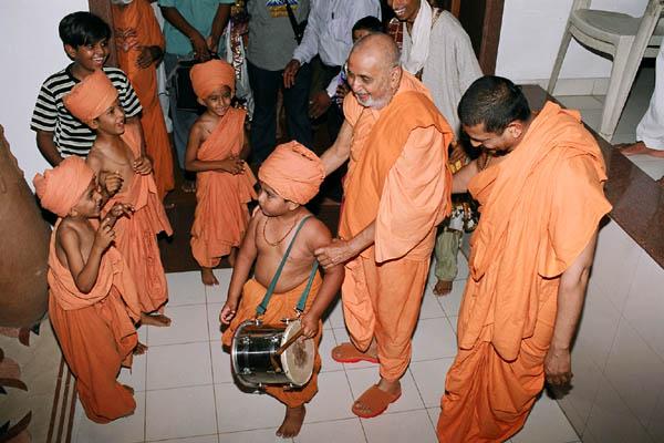 A balak welcomes Swamishri by playing a drum