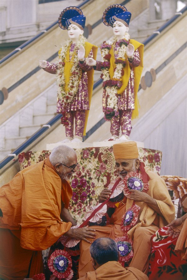 Pujya Balmukund Swami honors Swamishri with a garland