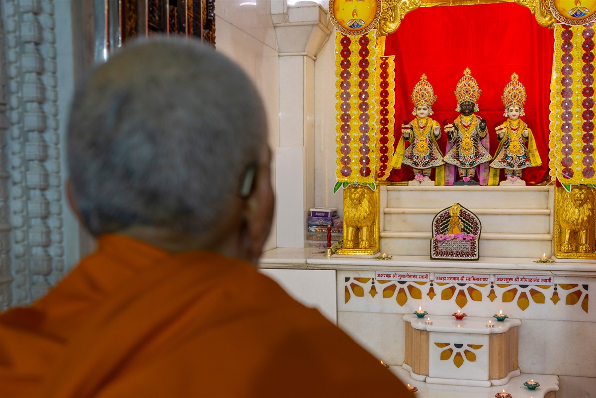 Swamishri engrossed in darshan of Bhagwan Swaminarayan, Aksharbrahma Gunatitanand Swami and Shri Gopalanand Swami