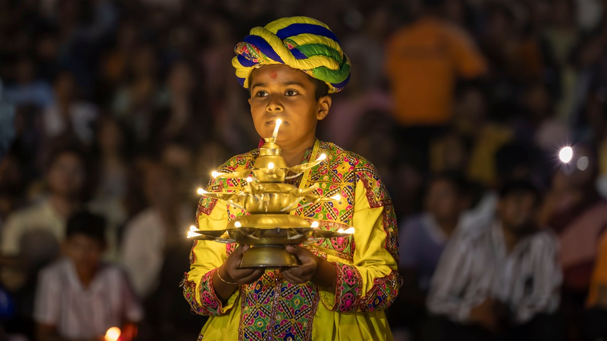 A child welcomes Swamishri with lamps