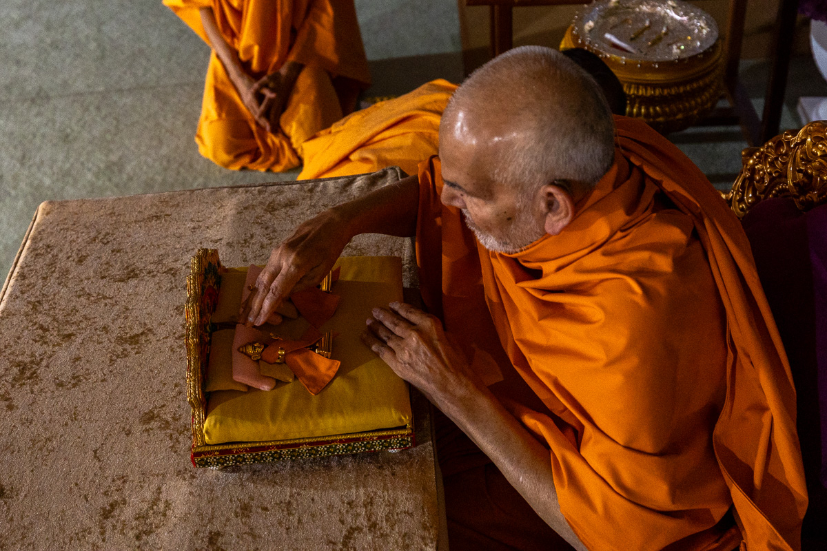 Swamishri engrossed in seva of Shri Harikrishna Maharaj and Shri Gunatitanand Swami Maharaj