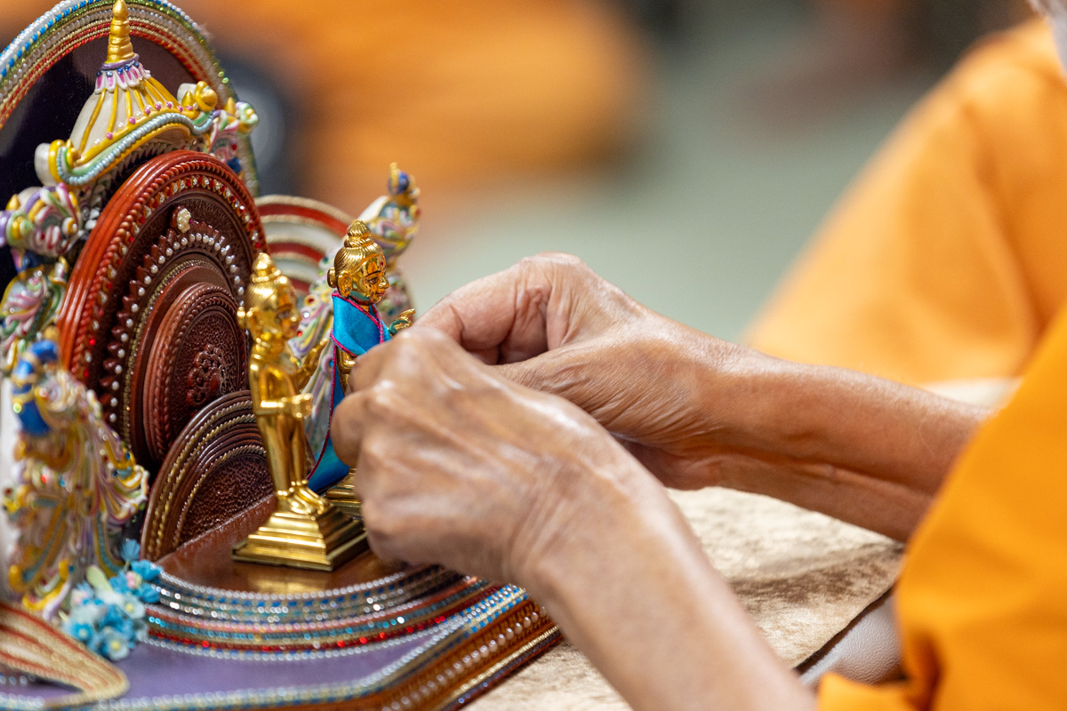 Swamishri adorns Shri Gunatitanand Swami Maharaj with garments