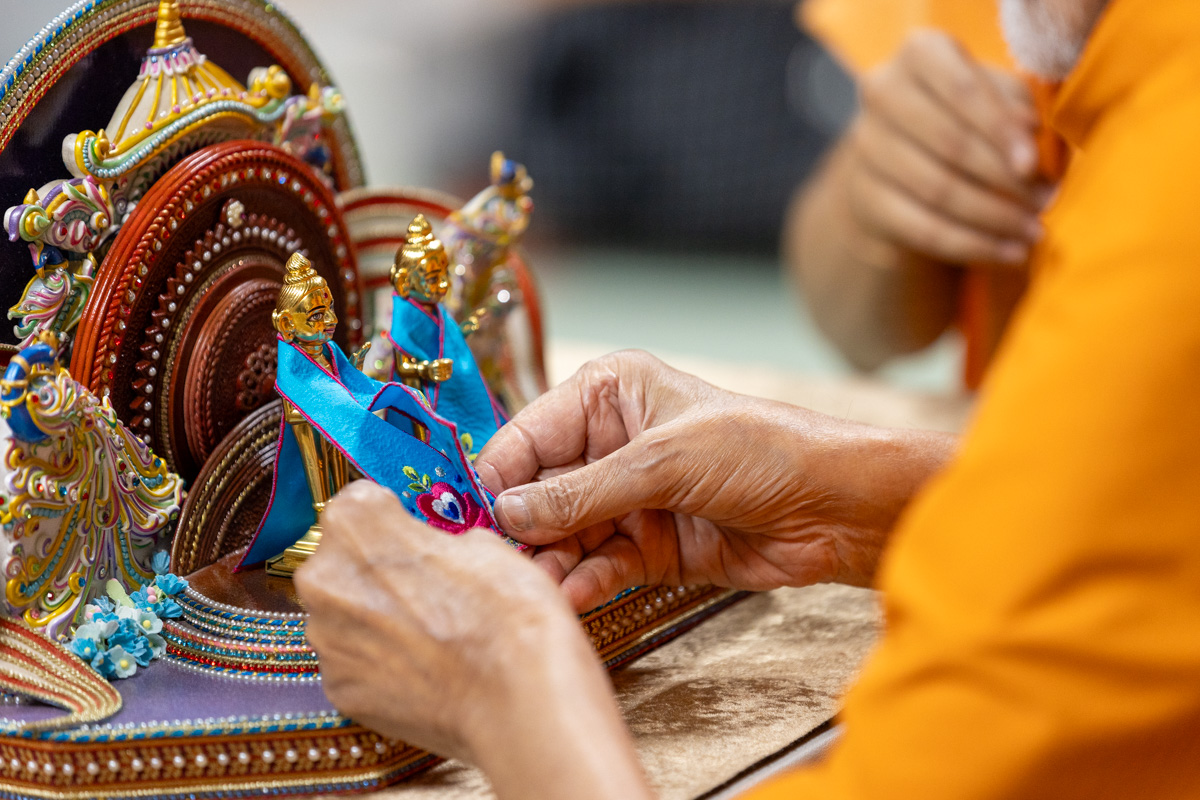 Swamishri adorns Shri Harikrishna Maharaj with garments