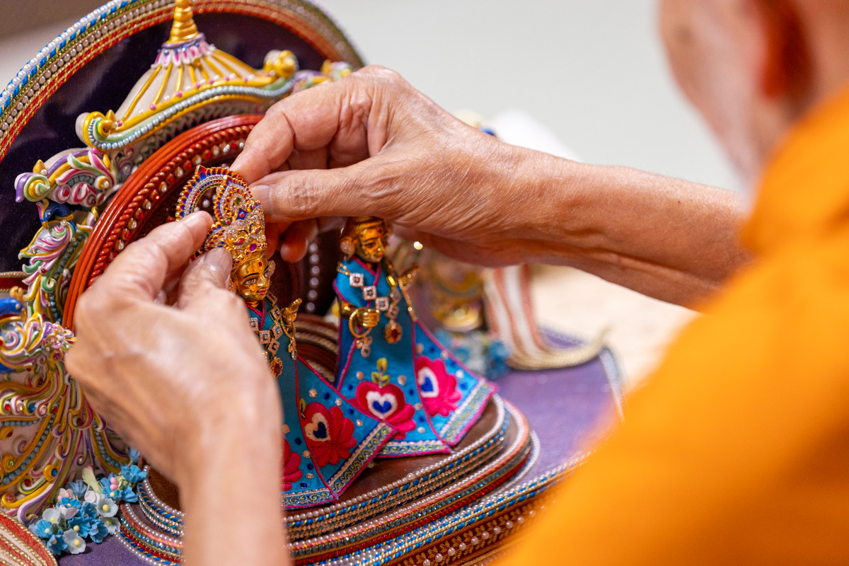 Swamishri adorns Shri Harikrishna Maharaj with ornaments