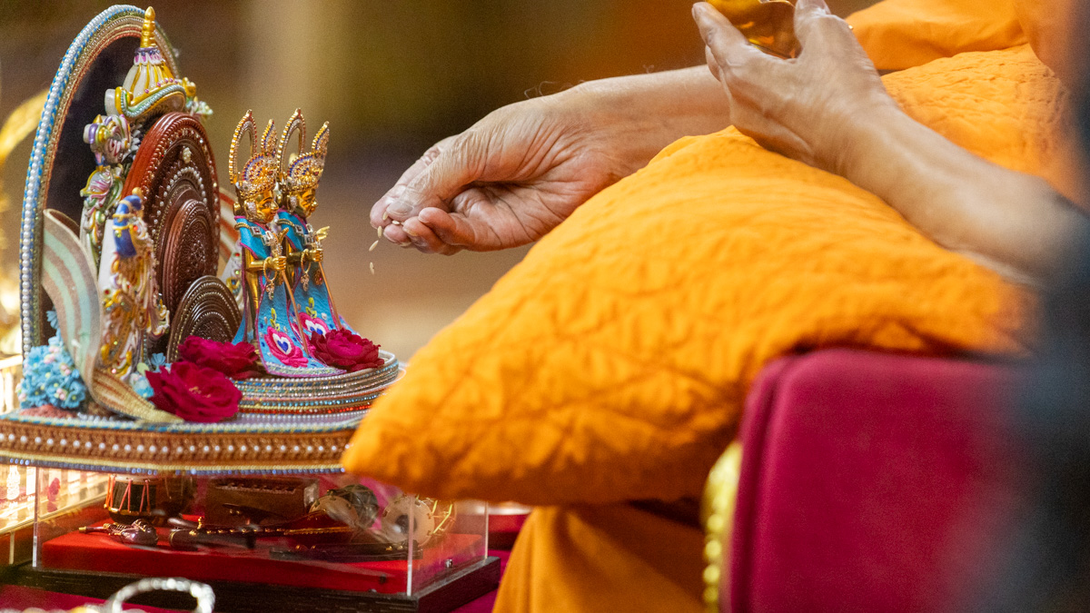 Swamishri offers rice grains during the recital of the Sahajanand Namavali