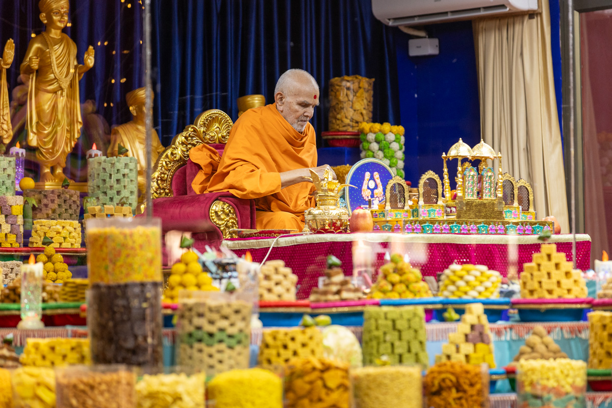 Swamishri offers rice grains during the recital of the Sahajanand Namavali