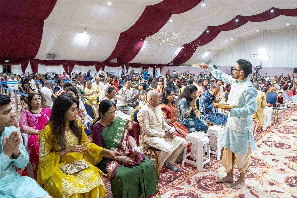 The Pujari sprinkles sancitfied rice grains over devotees with blessings of peace and prosperity