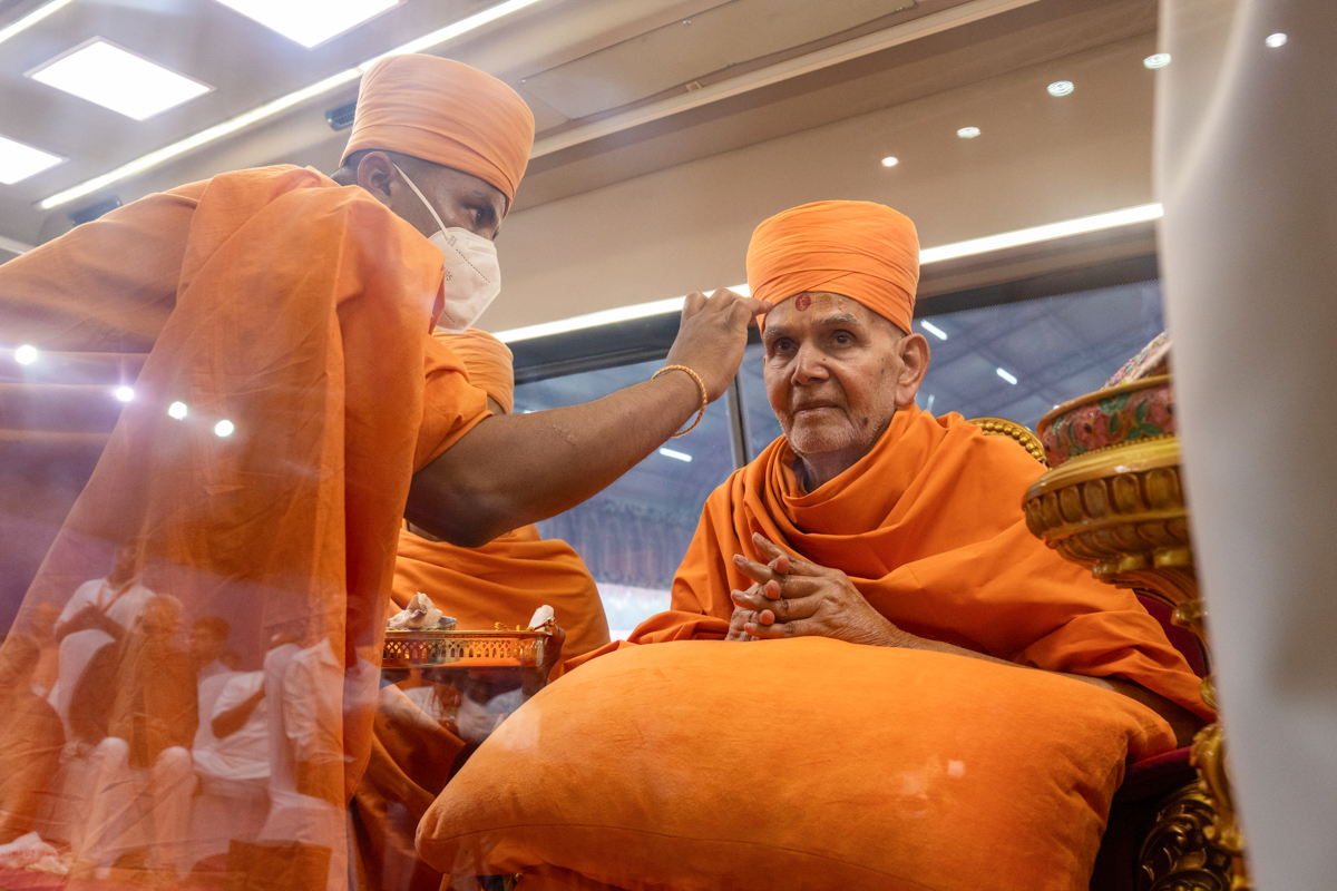 A swami applies chandan archa to Swamishri