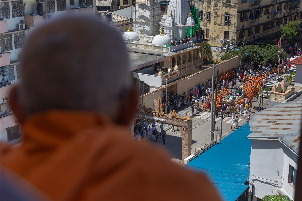 Swamishri observes the nagar yatra from the mandir gallery