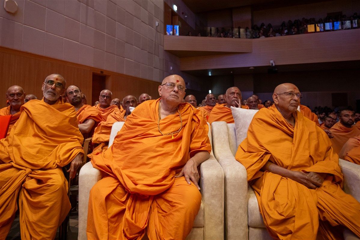 Senior swamis and swamis watch a skit performance by devotees