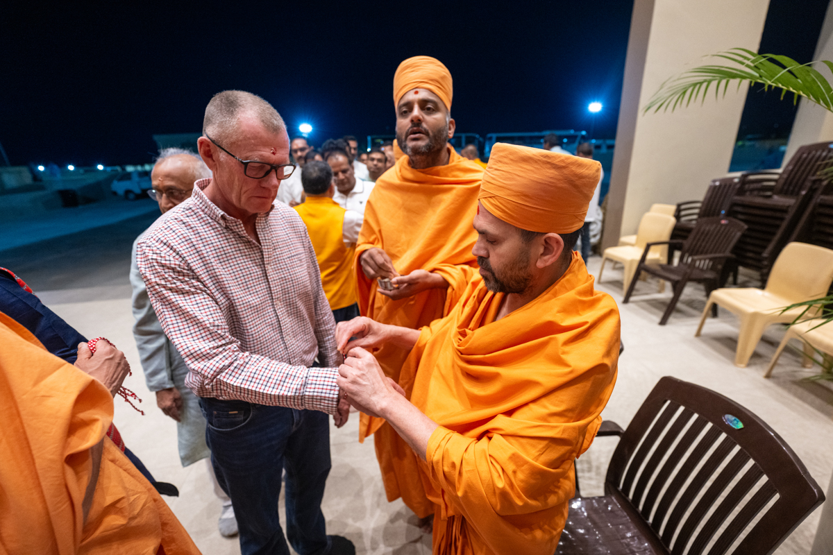 A swami ties a nadachhadi to a devotee