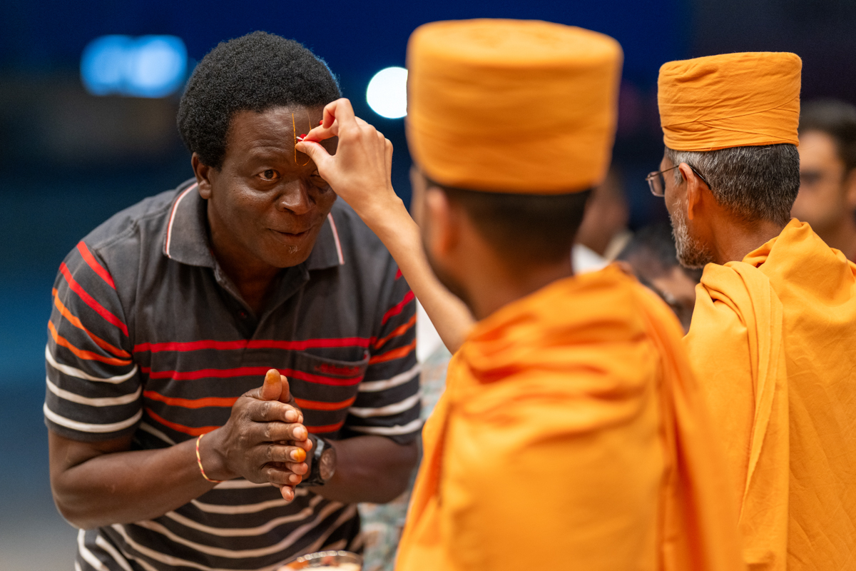 A swami applies a chandlo and rice  grains to a devotee