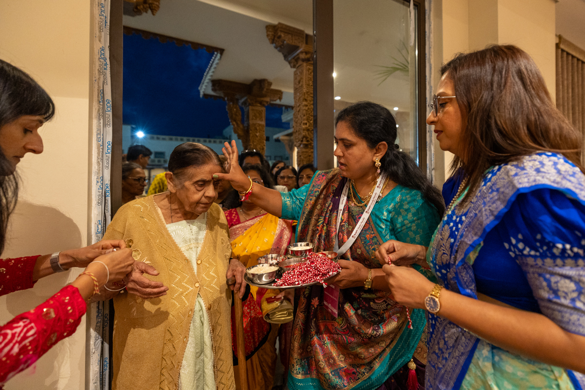 A karyakar applies a chandlo to a devotee