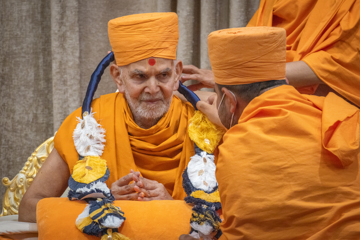 A swami honors Swamishri with a garland