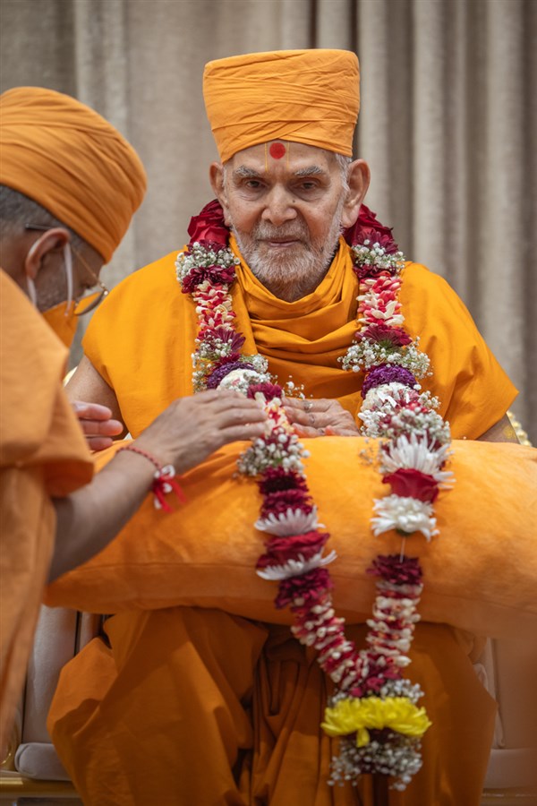 Priyavrat Swami honors Swamishri with a garland