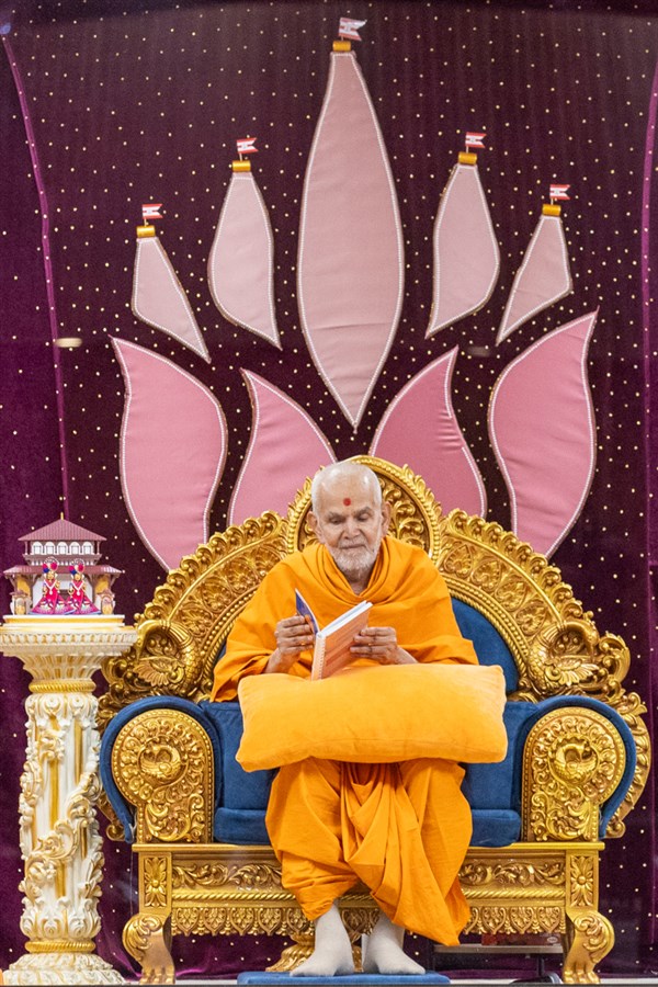 Swamishri observes a book