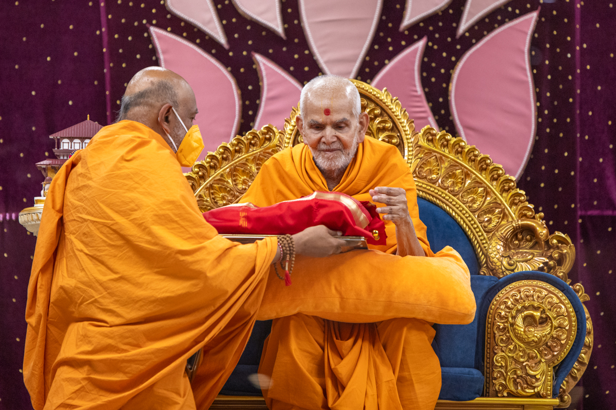 Swamishri observes a book