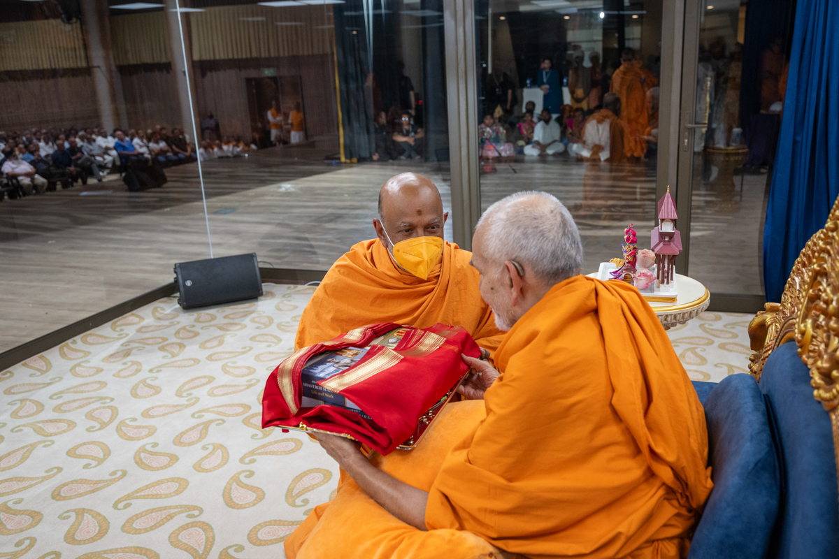 Swamishri observes a book