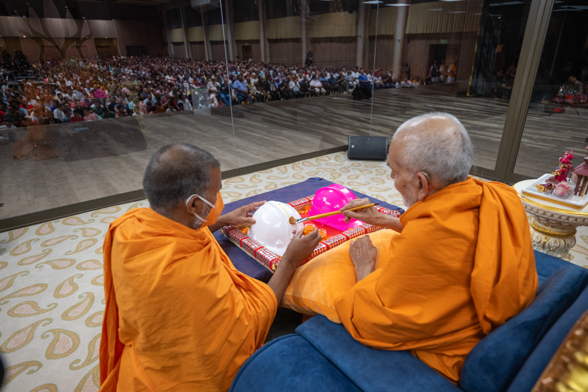 Swamishri paints on a helmet