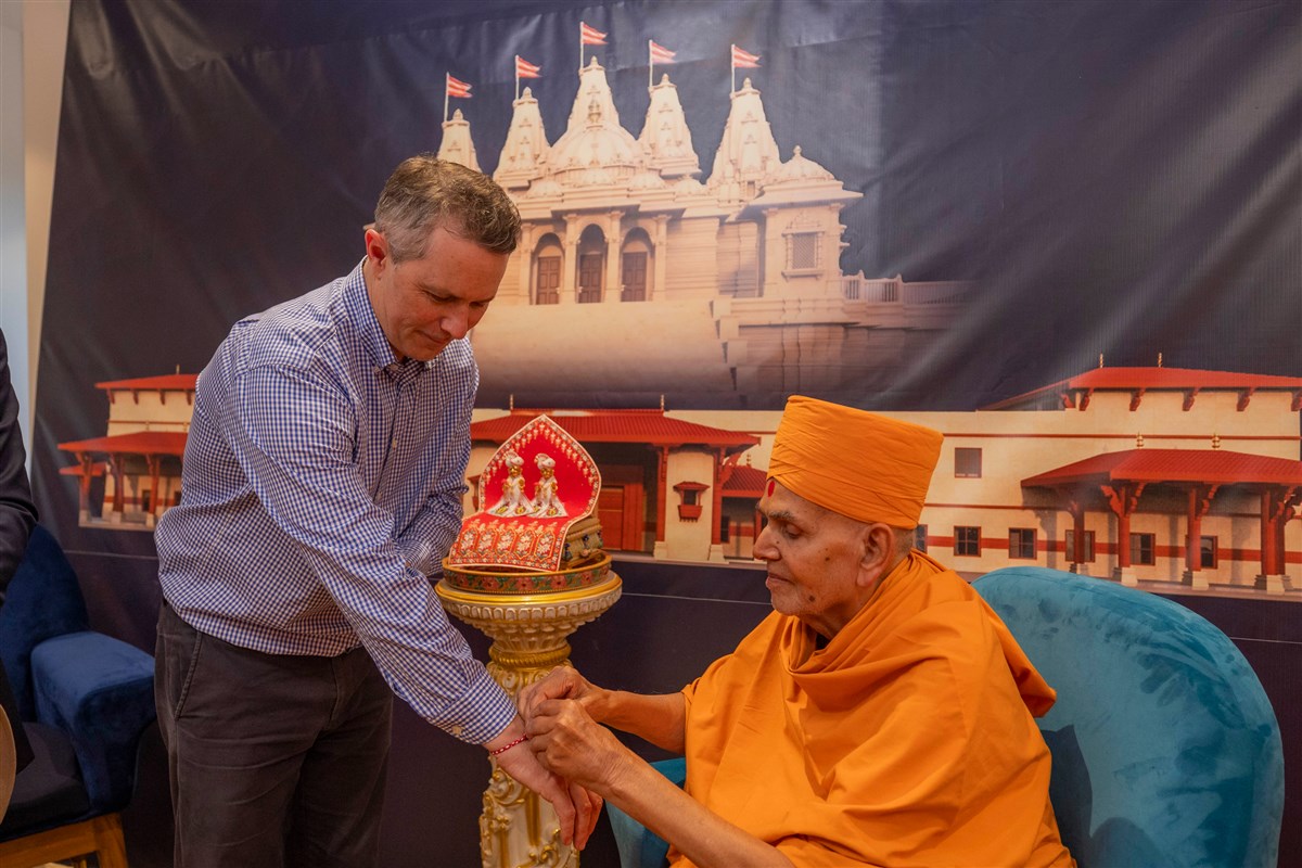 Mahant Swami Maharaj ties a nadachadi on the wrist of Hon Jason Clare, Minister for Education for Australia