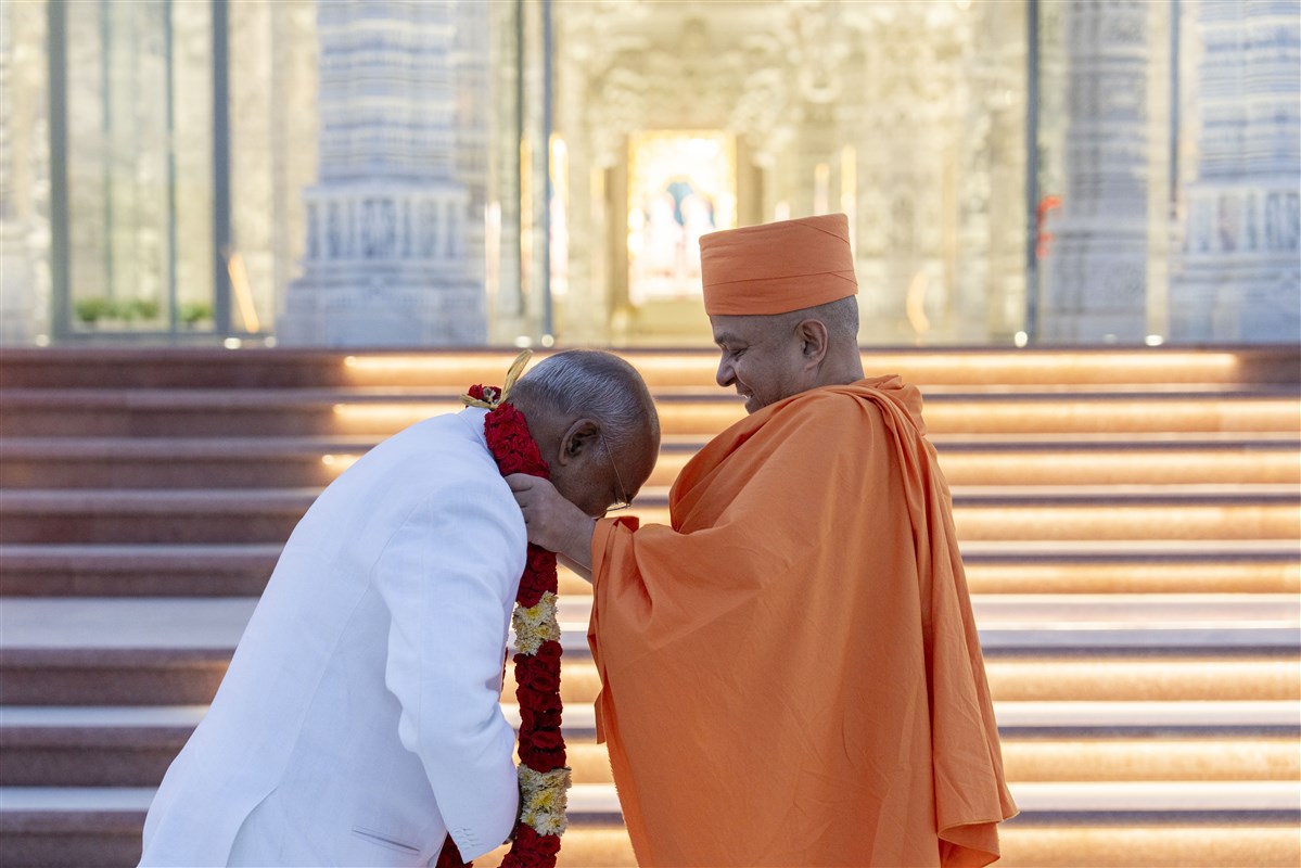 Swami Brahmaviharidas warmly welcomes Shri Ram Nath Kovind with a rose garland at the Mandir steps.