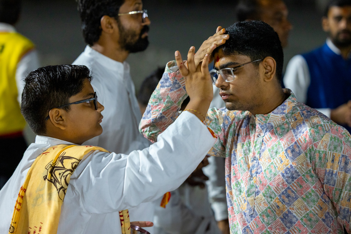 A balak applies a chandlo to a devotee