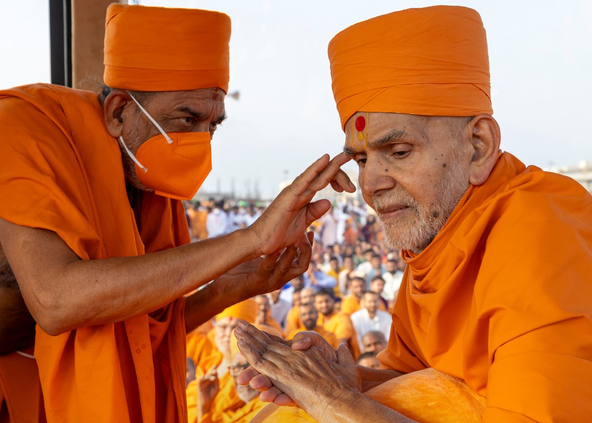 A swami applies chandan archa to Swamishri