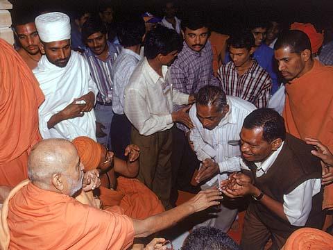 Swamishri giving a rosary in appreciation to each Tandel volunteer