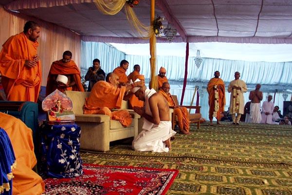 Pujya Doctor Swami gives the gatariyu and Pujya Mahant Swami places the pagh on each parshad