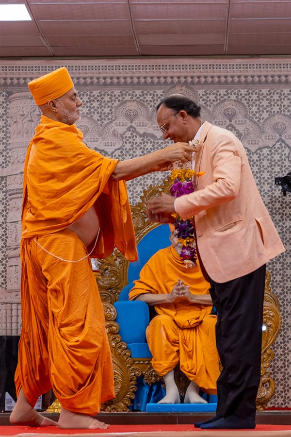 Pujya Viveksagar Swami honors a dignitary with a garland