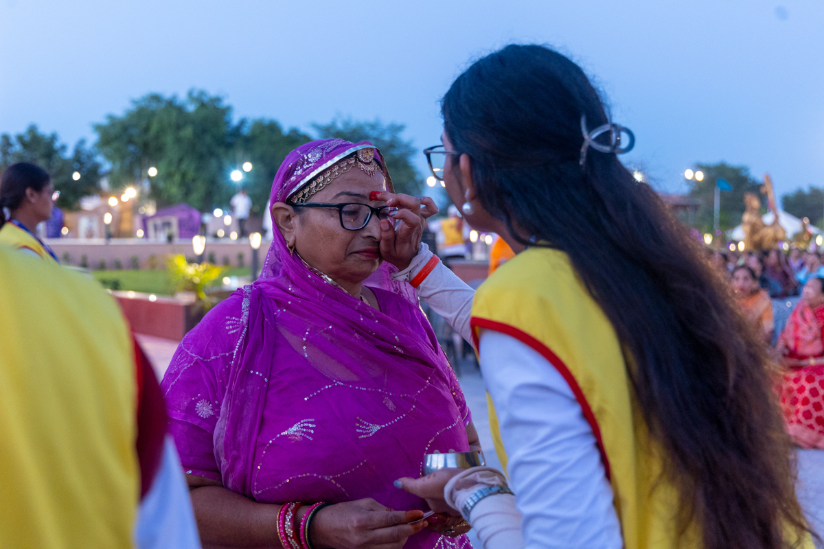 A karyakar applies a chandlo to a devotee