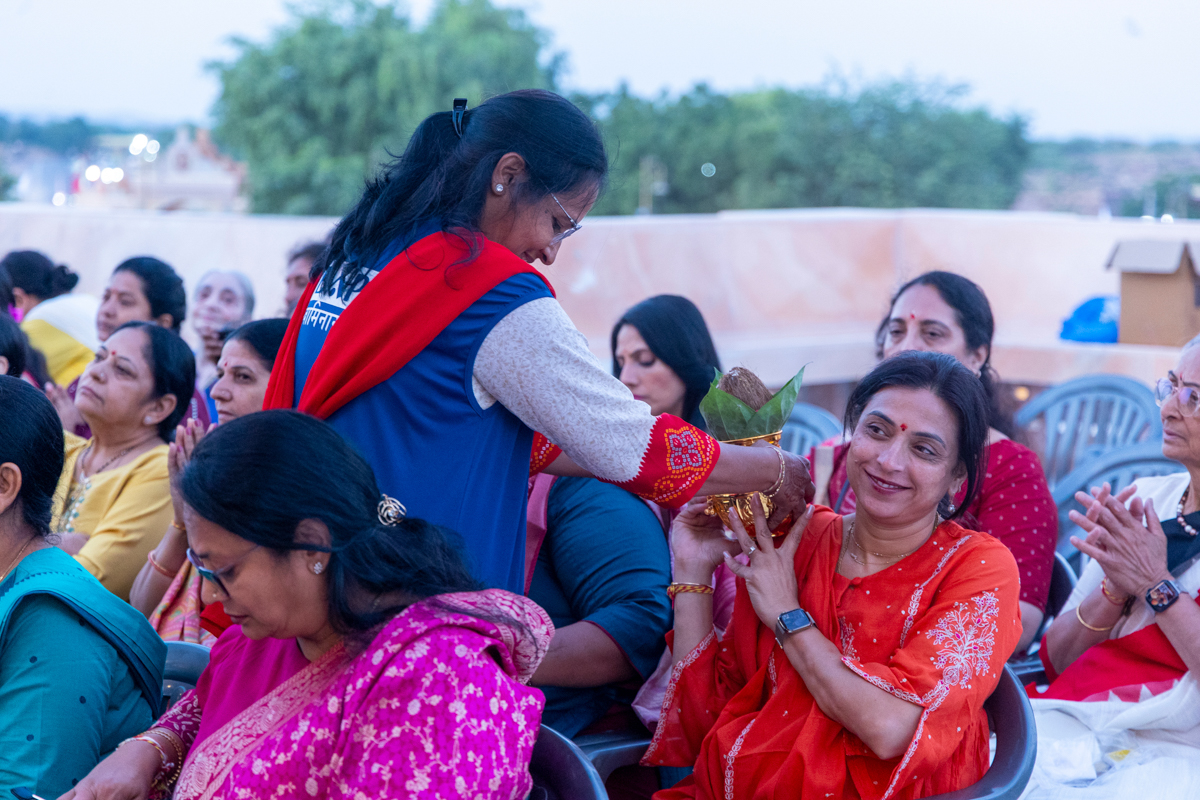 A karyakar touches a kalash to the shoulder of a devotee