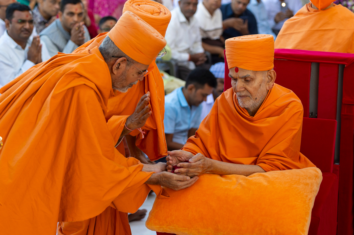 Swamishri gives flowers to Aksharcharan Swami to perform pujan of the murtis