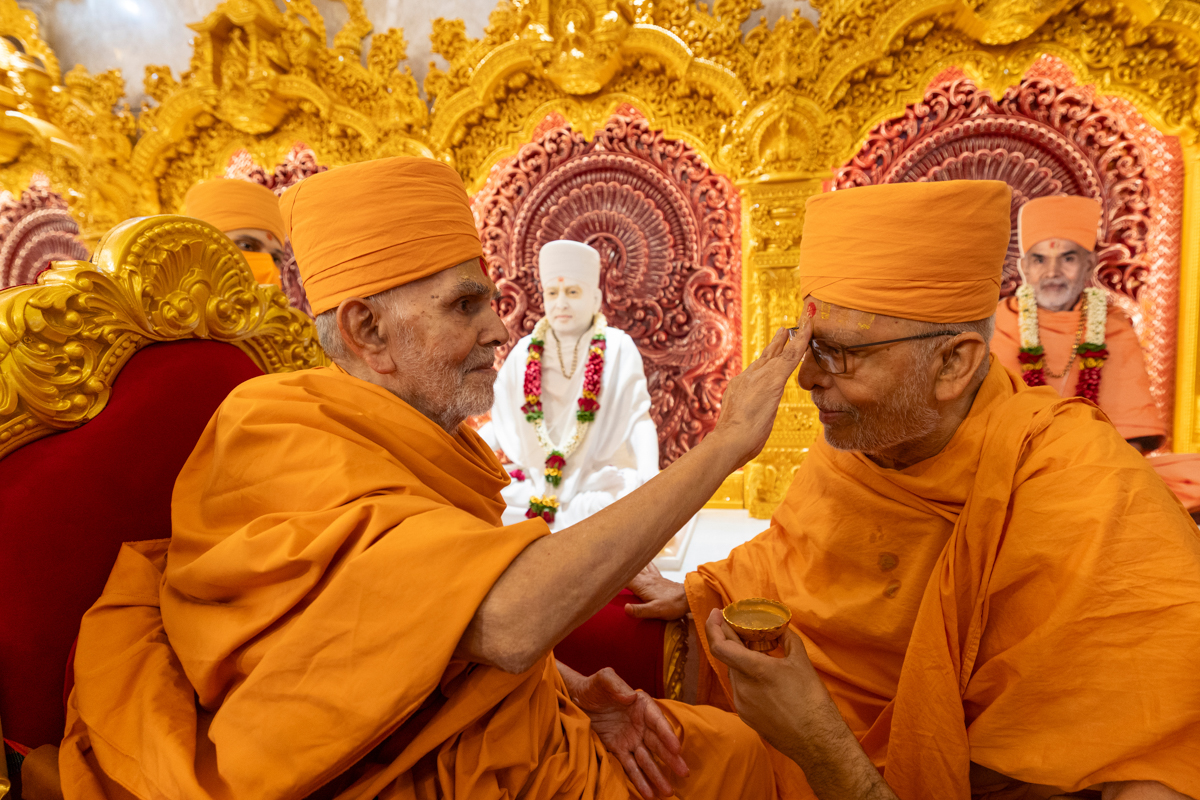 Swamishri applies chandlo to Pujya Ghanshyamcharan Swami