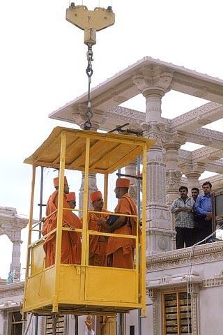 Being elevated to the mandir floor in a cabin by the construction crane
