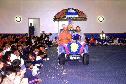 Thakorji and Swamishri are welcomed with a shower of flower petals in the Shibir