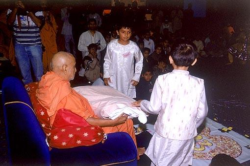 Children's Session - Swamishri takes up 323 balaks on his lap! - offering a pillow signed by 323 balaks symbolizes their presence on Swamishri's lap