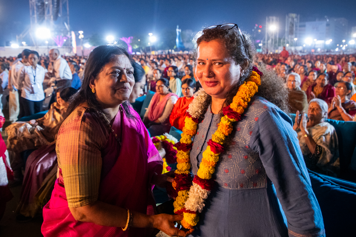 A karyakar honors a dignitary with a garland