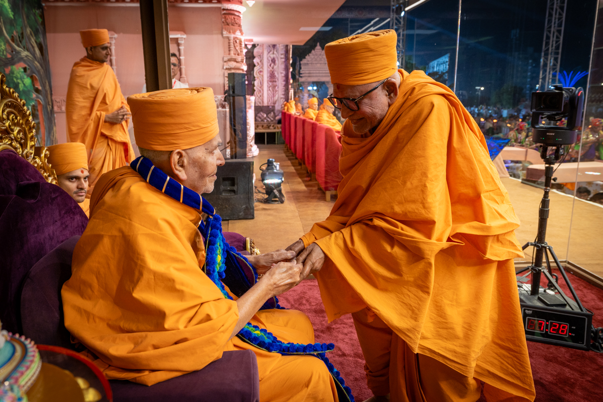 Pujya Bhaktipriya Swami (Kothari Swami) honors Swamishri with a garland