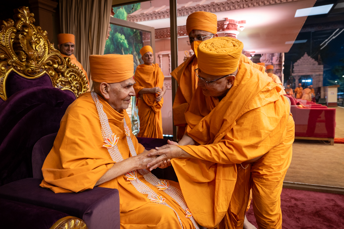 Pujya Ishwarcharan Swami honors Swamishri with a garland
