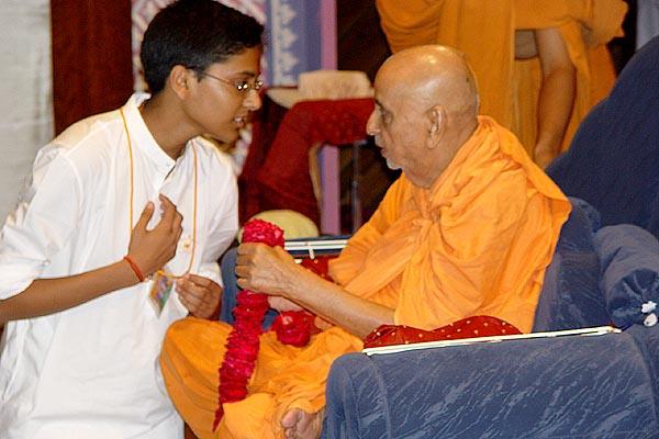 A kishore from the UK welcomes Swamishri with a garland