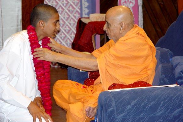 A kishore from the USA welcomes Swamishri with a garland