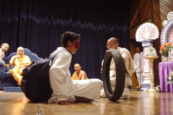 A blind-folded kishore is guided by Swamishri through an obstacle course