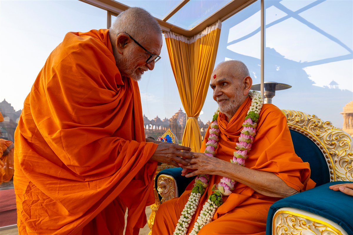 Pujya Kothari Swami honors Swamishri with a garland