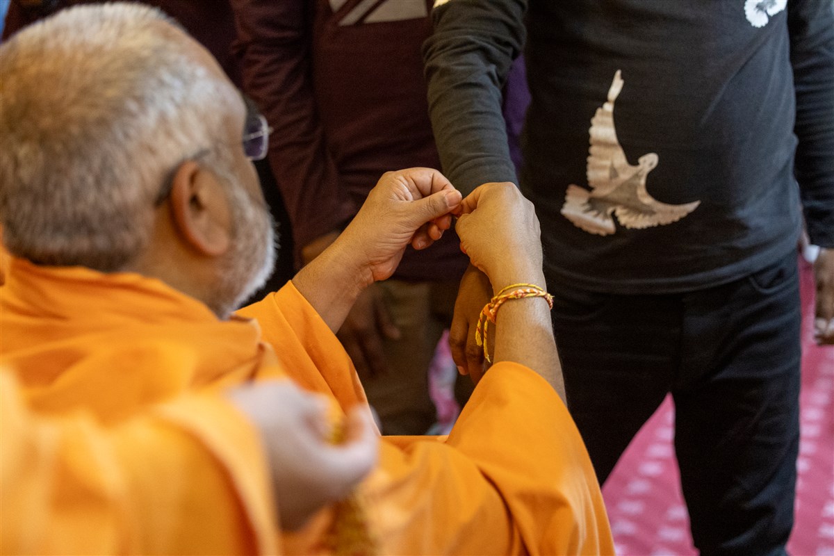 Yogvivek Swami ties a nadachhadi to a volunteer