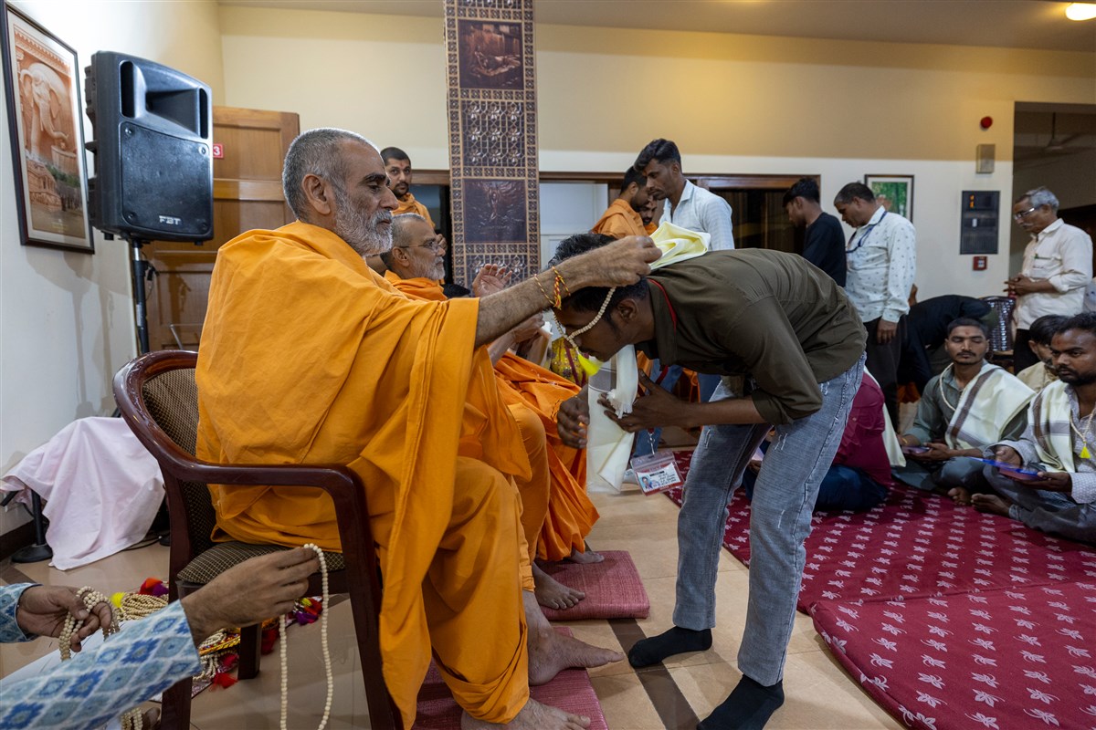Anandswarup Swami offers a mala to a volunteer