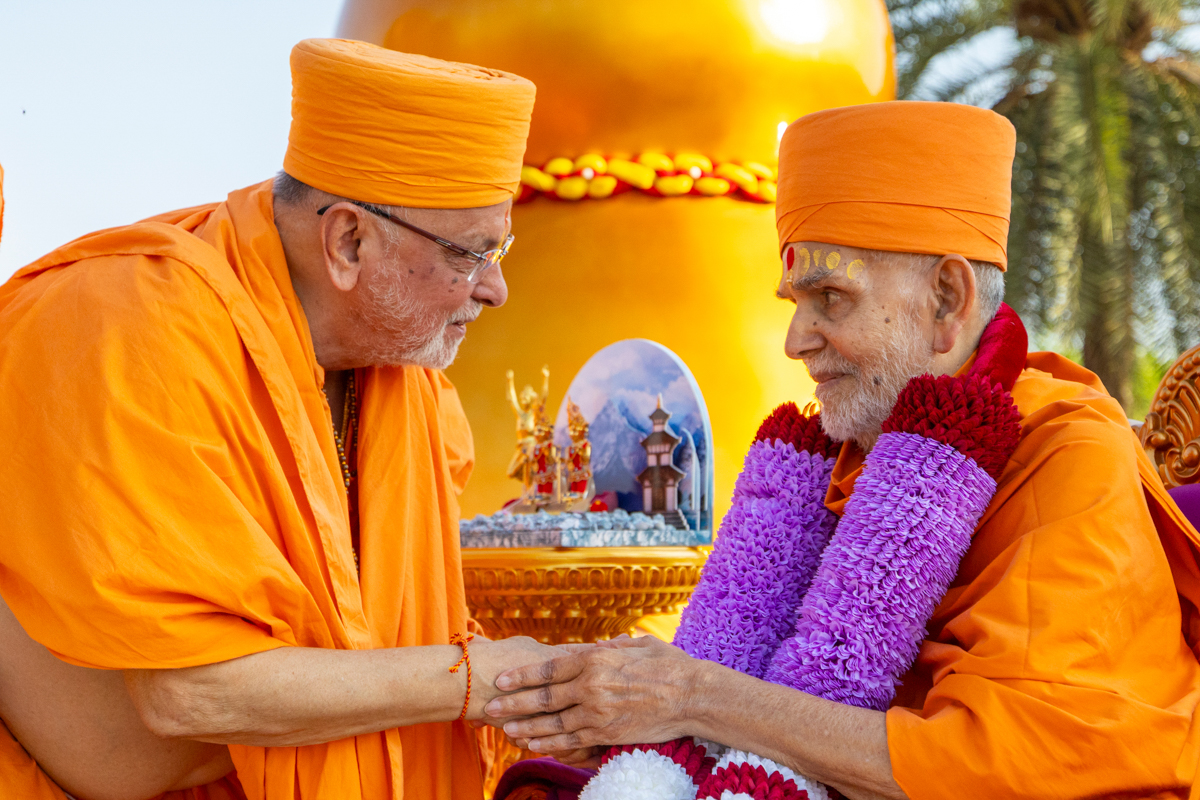 Pujya Ishwarcharan Swami honors Swamishri with a garland
