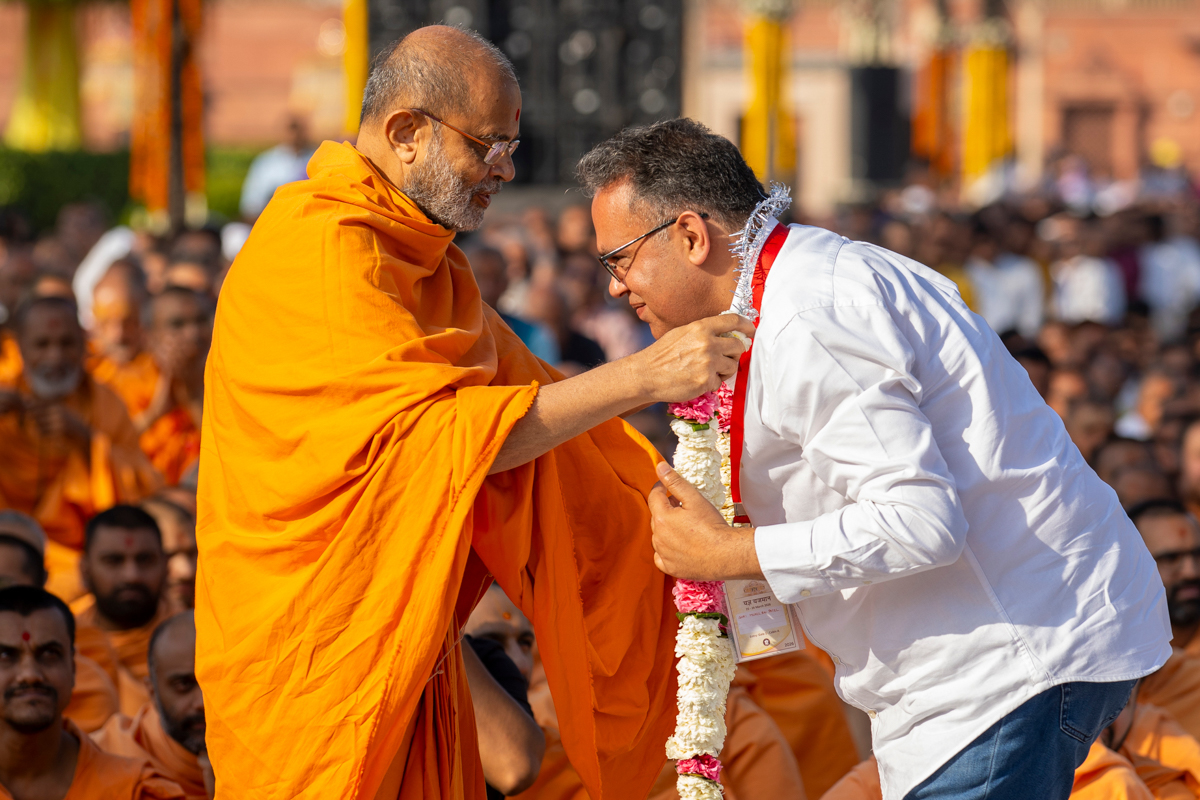 Gnaneshwar Swami honors a devotee with a garland