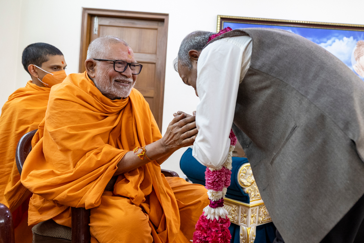 Pujya Kothari Swami honors a dignitary with a garland