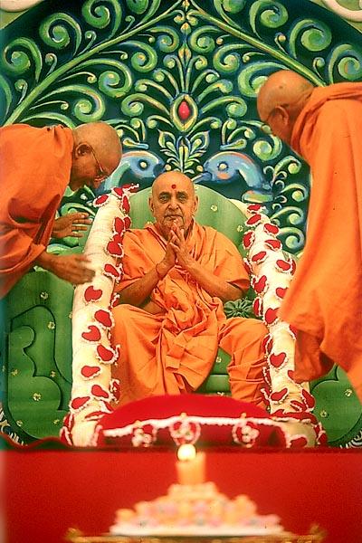 Senior sadhus offer a garland to Swamishri